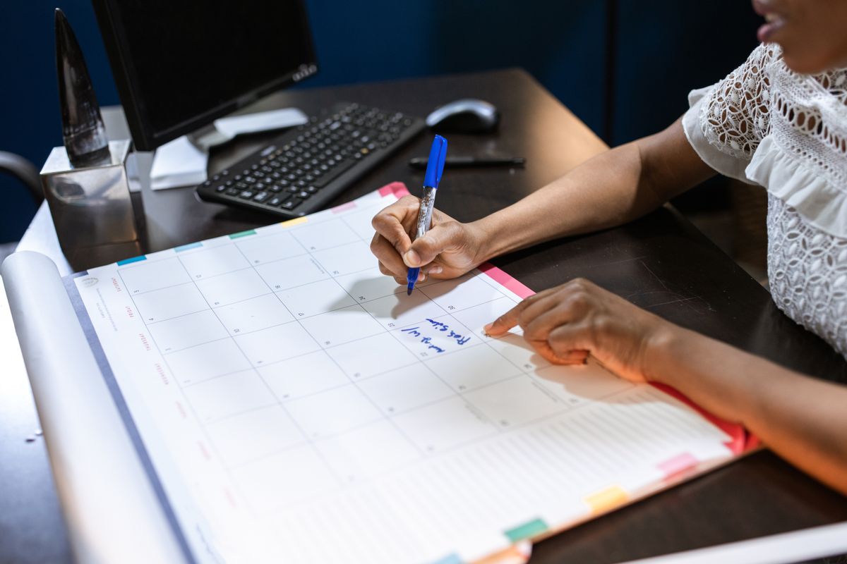 Persona anota fechas en un calendario de escritorio