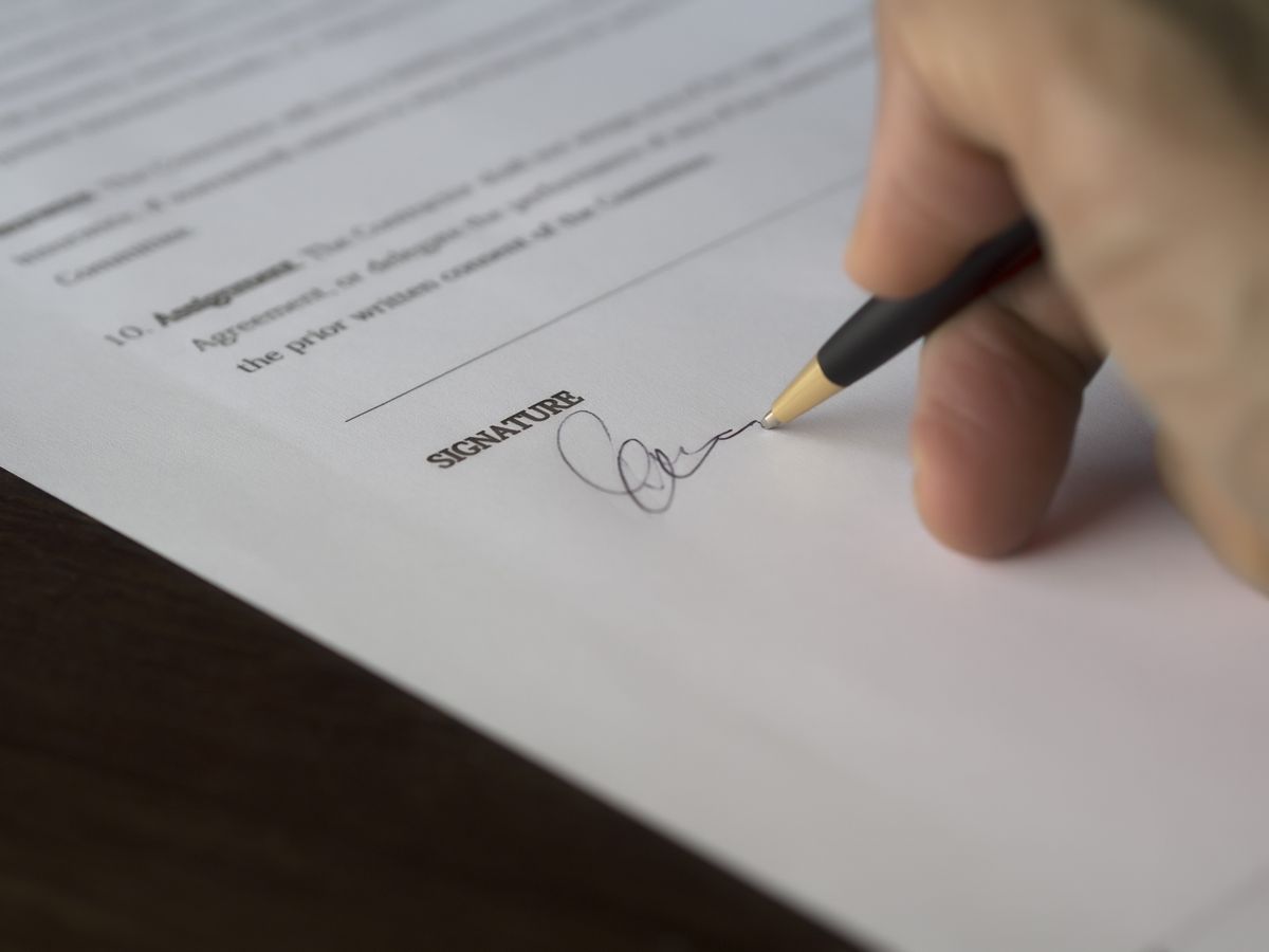 Mano firmando un documento con pluma